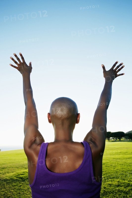 African American woman with arms outstretched in park