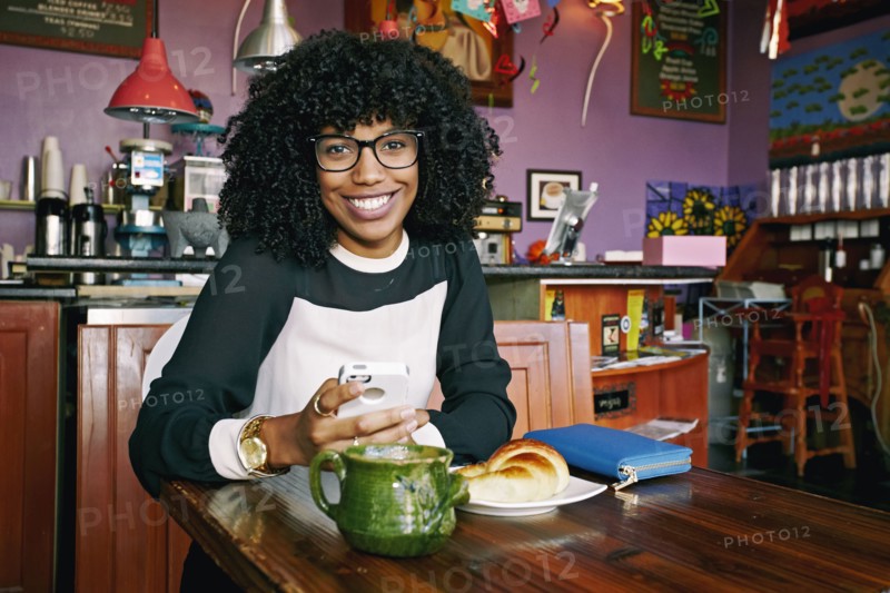 Mixed race woman using cell phone in cafe