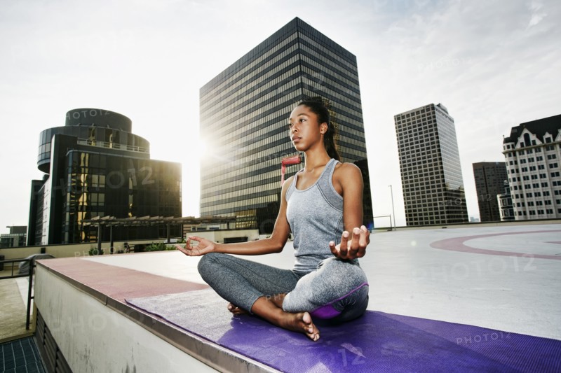 African American woman meditating on urban rooftop