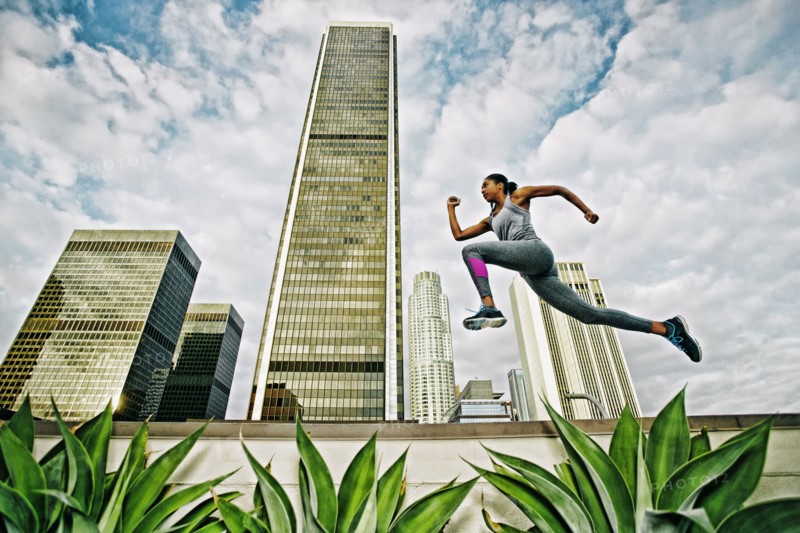 African American woman leaping on urban rooftop