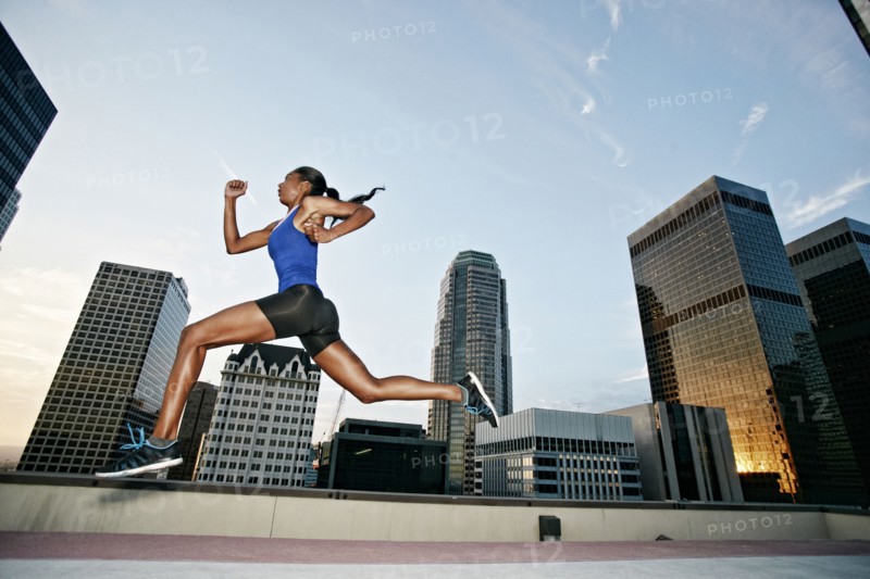 African American woman leaping on urban rooftop