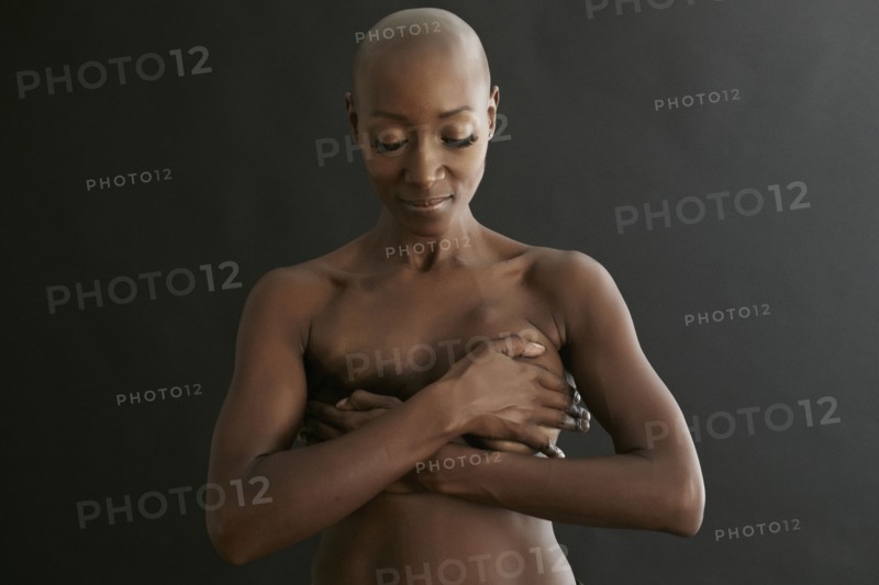 Nude African American cancer survivor covering her breasts