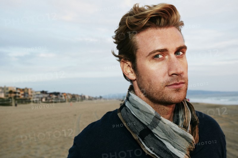 Serious Caucasian man standing on beach