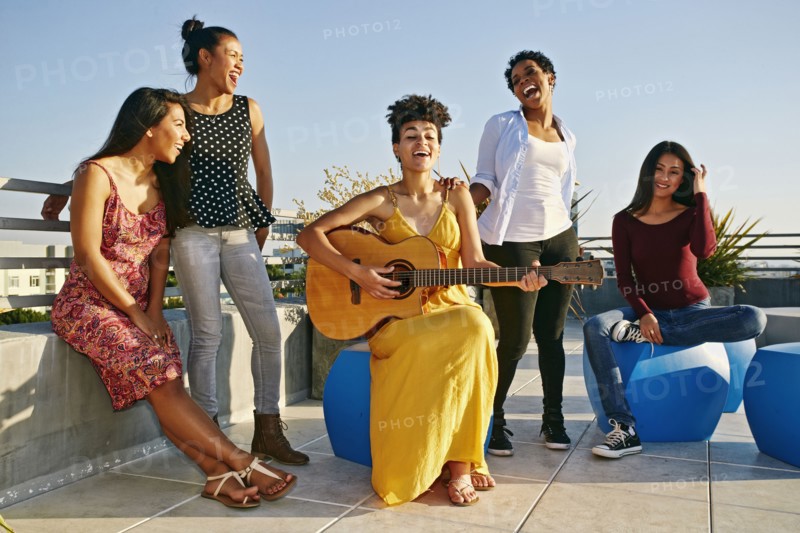 Women playing music and singing on urban rooftop