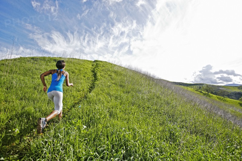 Black athlete running on rural hillside