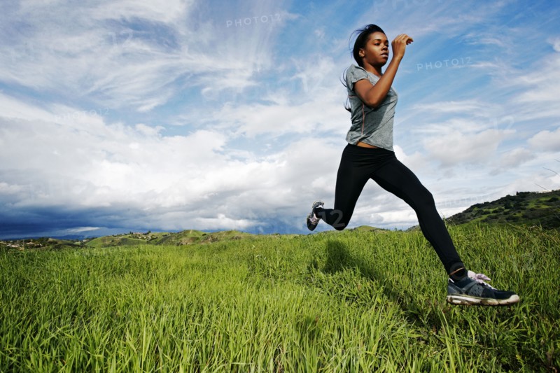 Black athlete running in rural field