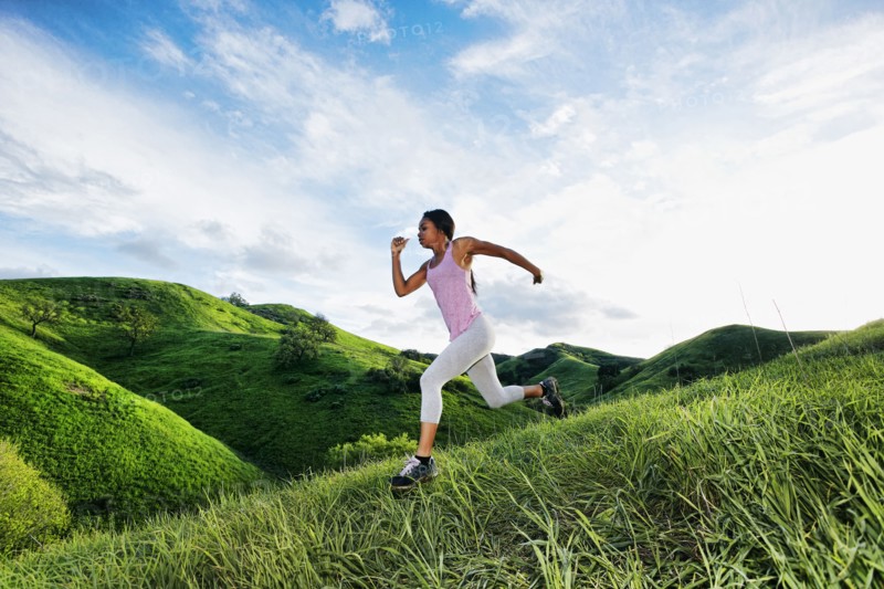 Black athlete running on rural hillside