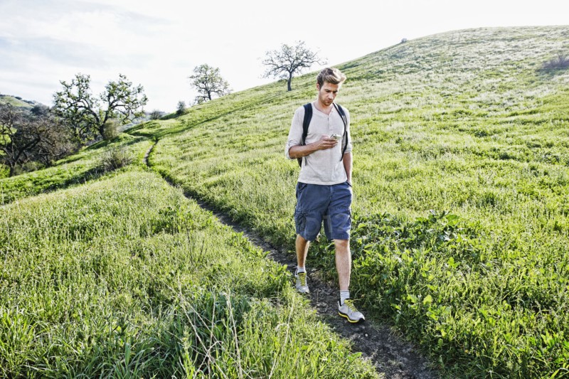 Caucasian man using cell phone on dirt path