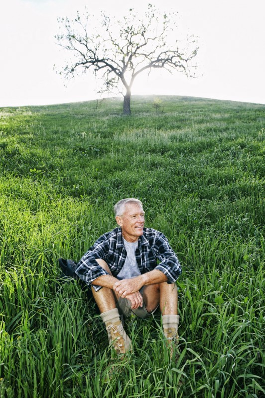 Older Caucasian man sitting on grassy hillside