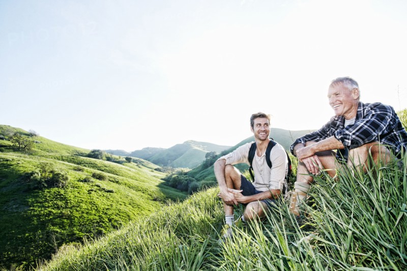 Caucasian father and son sitting on grassy hillside