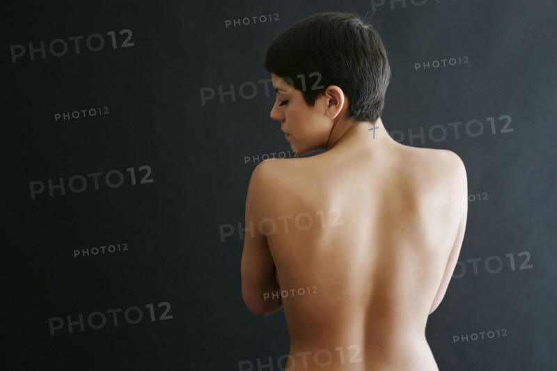 Rear view of nude Hispanic woman with tattoo on neck