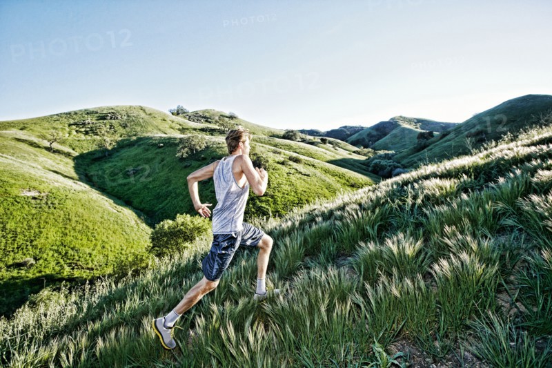 Caucasian athlete running on rural hills