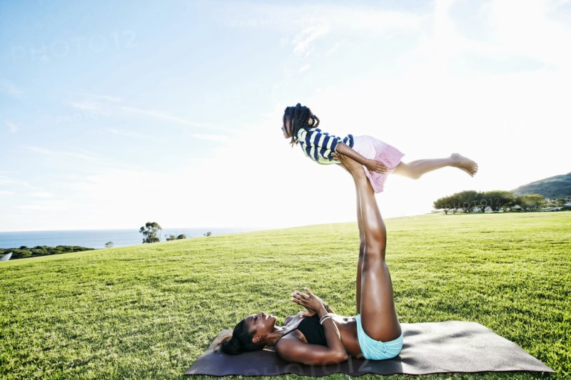 Mother holding daughter with legs in park