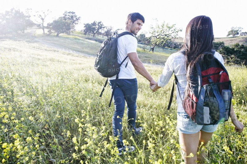 Couple carrying backpacks in field