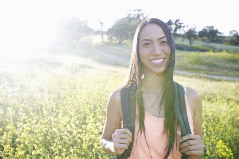 Mixed race woman carrying backpack in field