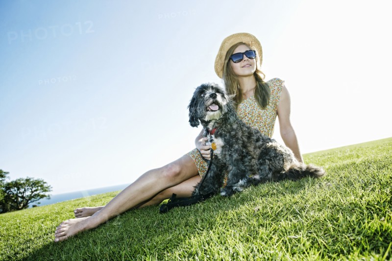 Caucasian woman sitting in field with dog