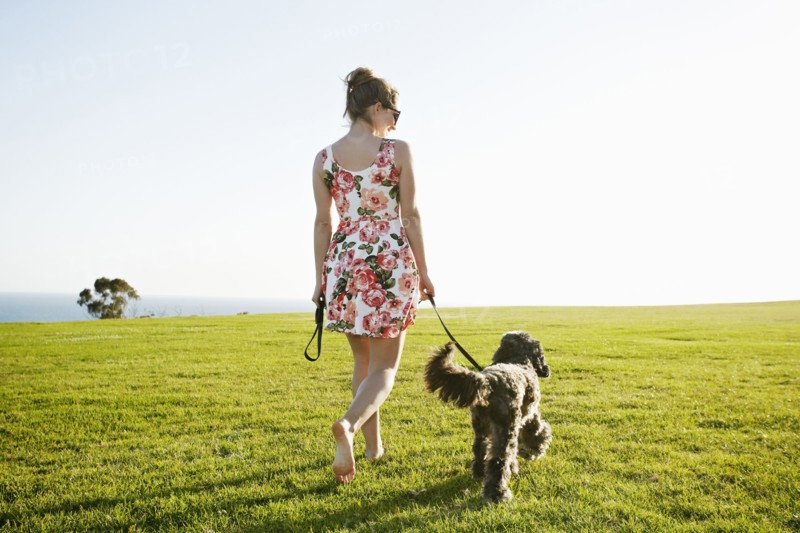 Caucasian woman walking dog in field