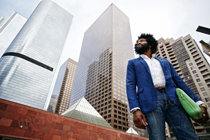 Mixed race businessman walking under skyscrapers