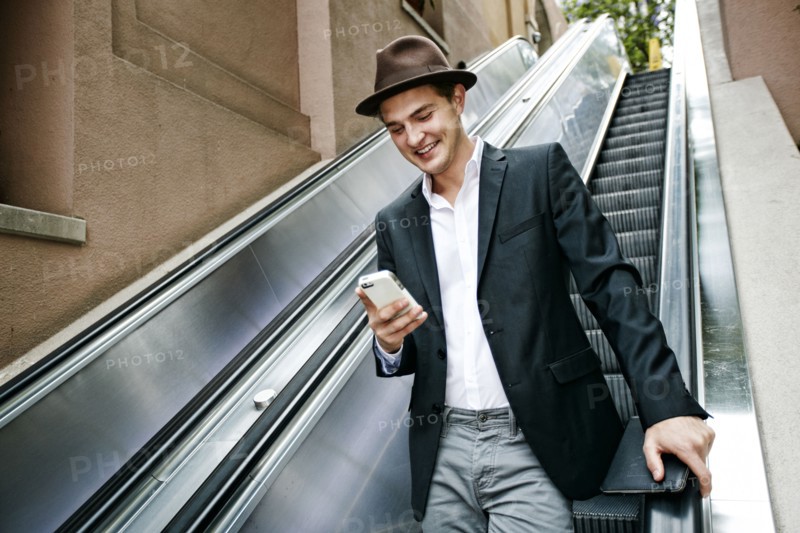 Caucasian businessman using cell phone on escalator