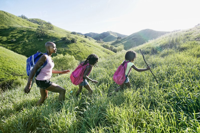 Black mother and daughters walking on rural hillside