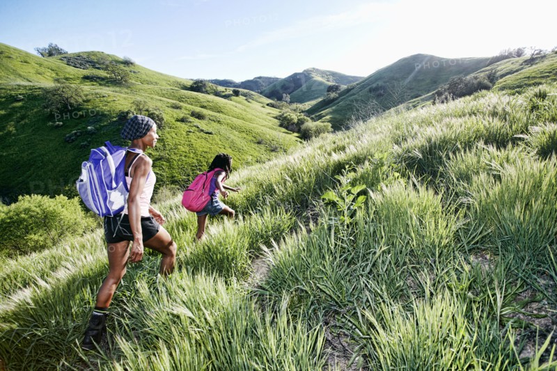 Black mother and daughter walking on rural hillside