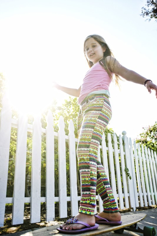 Caucasian girl riding skateboard on sidewalk