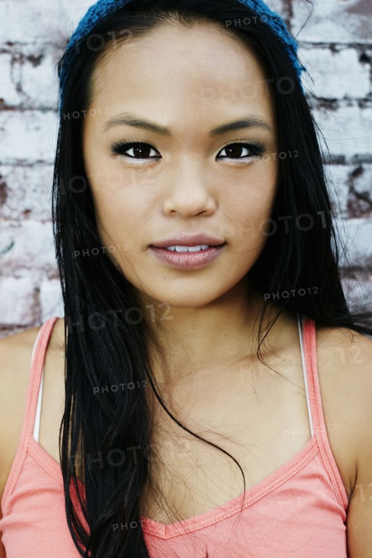Serious Asian woman at brick wall