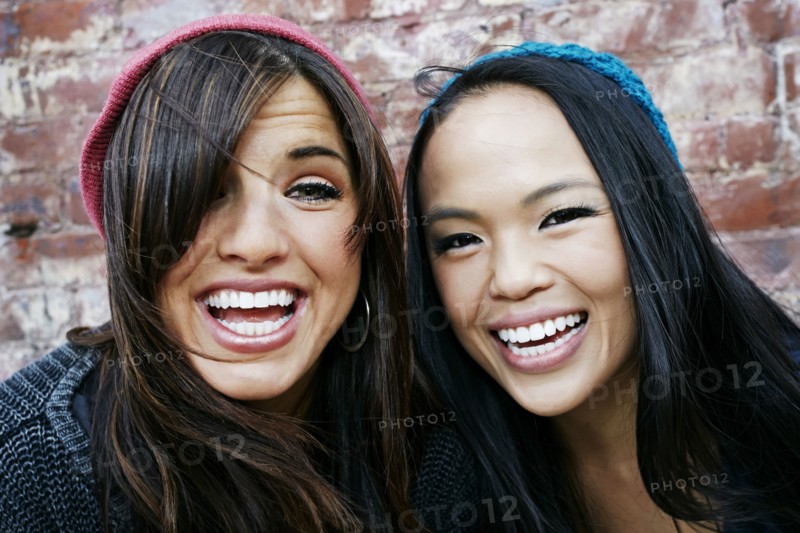 Women laughing in front of brick wall