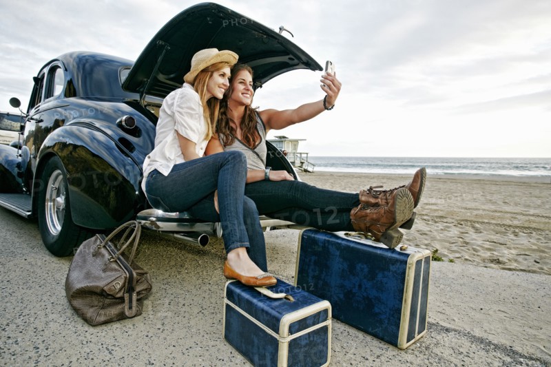 Women with luggage and vintage car on beach