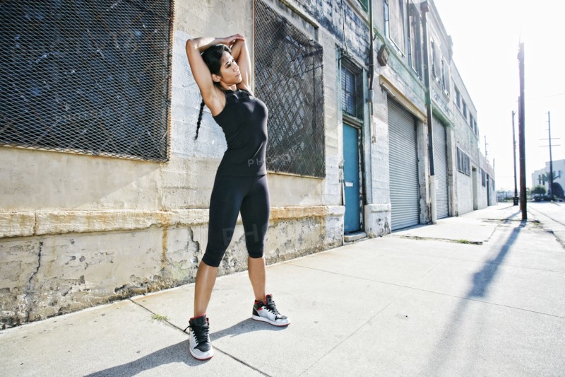 Mixed race woman stretching on sidewalk