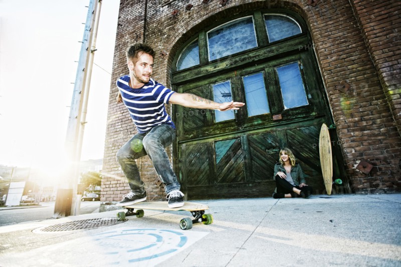 Caucasian man riding skateboard on sidewalk
