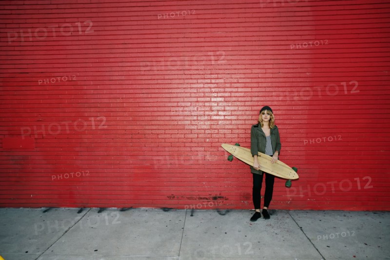 Caucasian woman holding skateboard on sidewalk