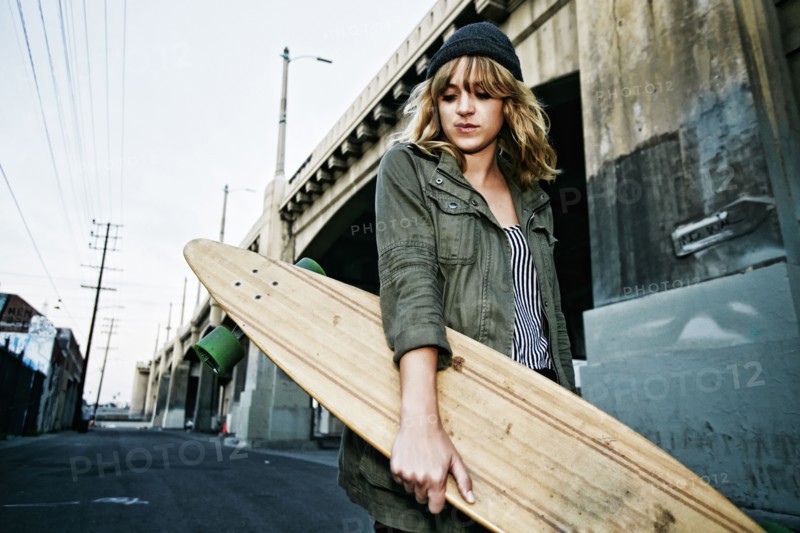 Caucasian woman carrying skateboard outdoors