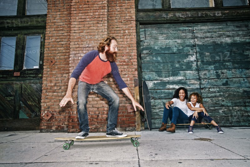 Family riding skateboards on sidewalk