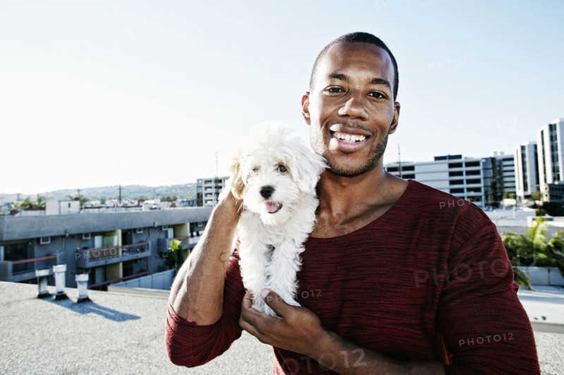African American man holding dog on urban rooftop