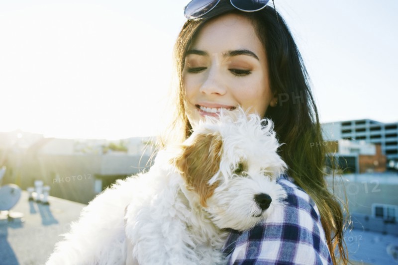 Mixed race woman holding dog on urban rooftop