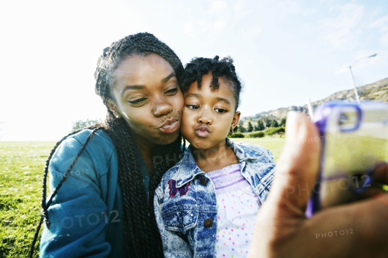 Black mother and daughter taking selfie outdoors
