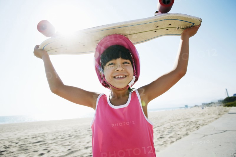 Mixed race girl holding skateboard at beach