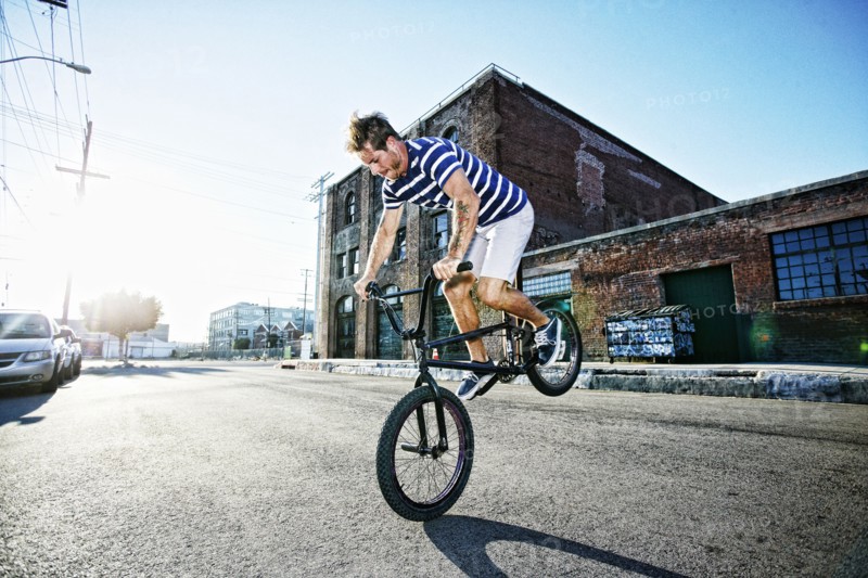 Caucasian man riding BMX bike on street