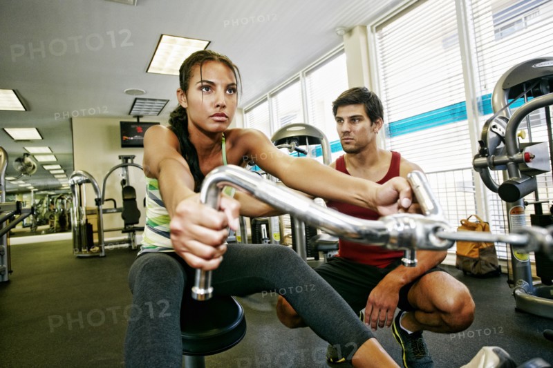 Woman working out with trainer in gymnasium