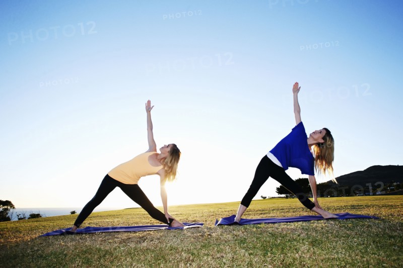 Caucasian women practicing yoga in field