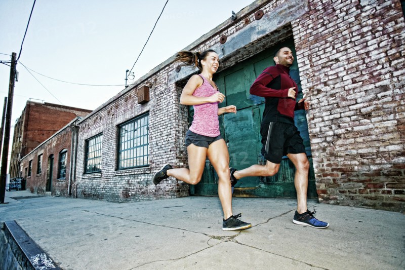 Caucasian couple jogging on sidewalk