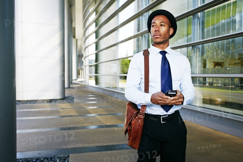 Black businessman using cell phone outside office building