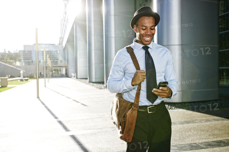 Black businessman using cell phone outside office building