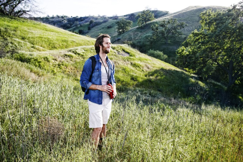 Caucasian hiker standing in grass on mountain holding water bottle