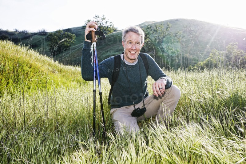 Caucasian hiker kneeling in grass on mountain
