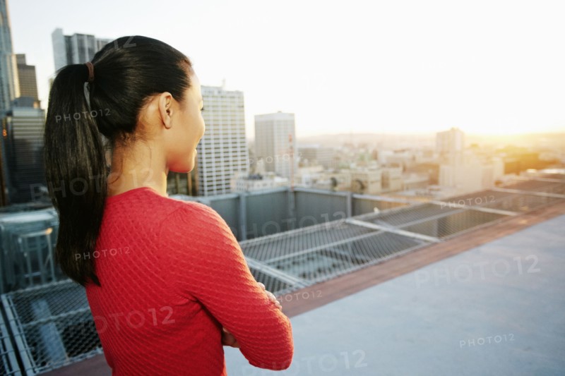 Mixed Race woman watching sunset on urban rooftop