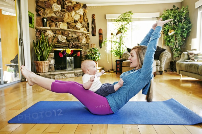 Mother working out on exercise mat with baby in lap