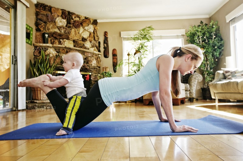 Mother working out on exercise mat with baby on legs
