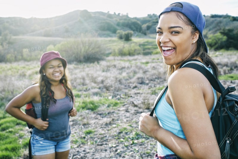 Mixed Race sisters backpacking in field